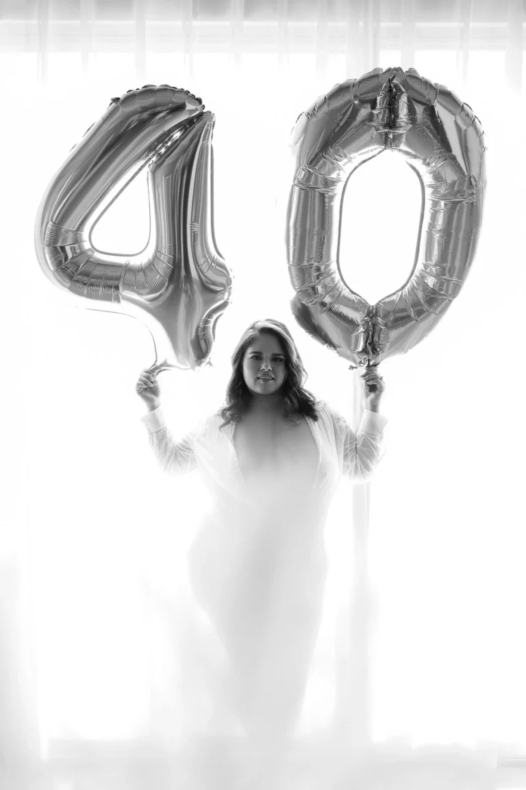 Black-and-white portrait of a woman holding silver 40th birthday balloons